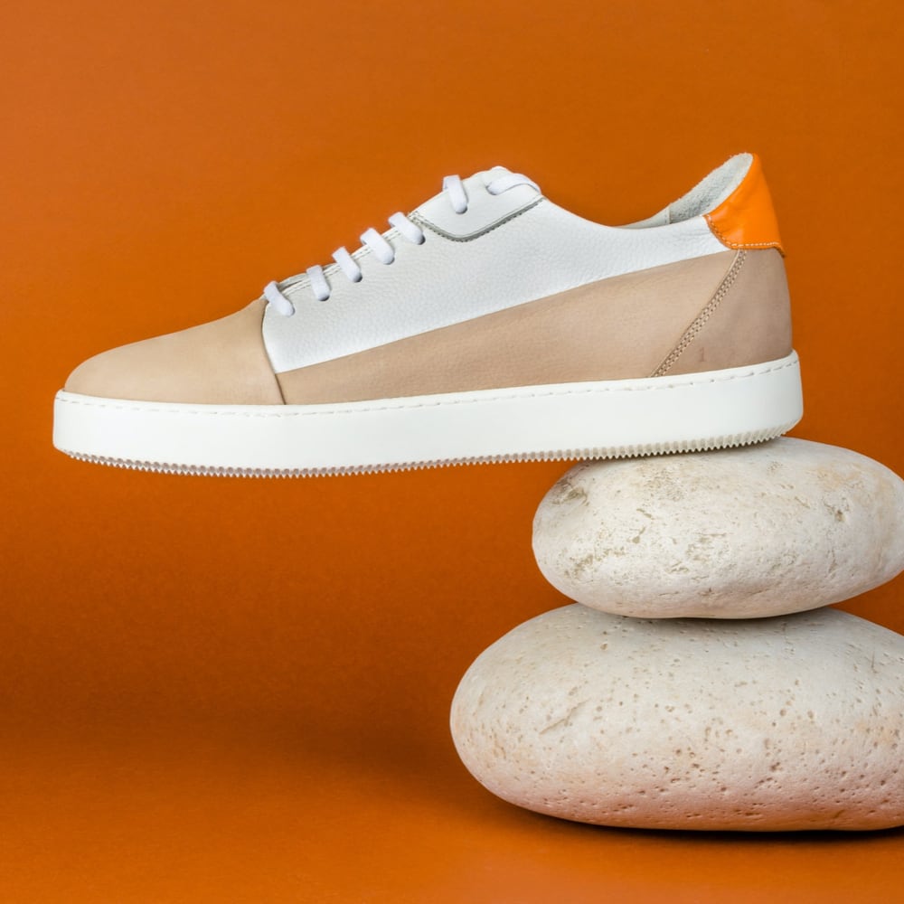 Galeria do produto, um par de sapatos com sola branca sobre um fundo laranja.